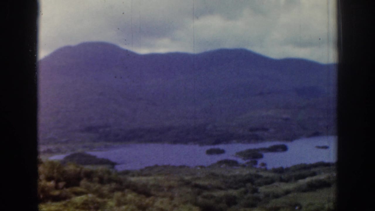 Wide blue water with small landforms at the foot of purple hills.