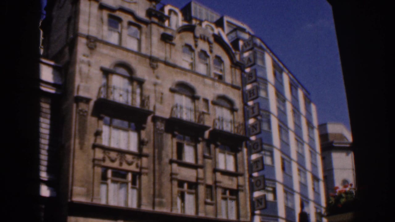 Ornate multi-story facade with balconies and a vertical WASHINGTON sign beside a modern building.