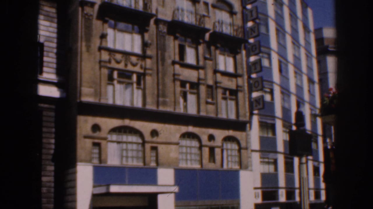 1961 Ireland frame showing the building's lower stories, decorative windows, blue panels, and adjacent WASHINGTON sign.