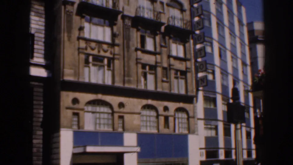 1961 Ireland frame showing the building's lower stories, decorative windows, blue panels, and adjacent WASHINGTON sign.