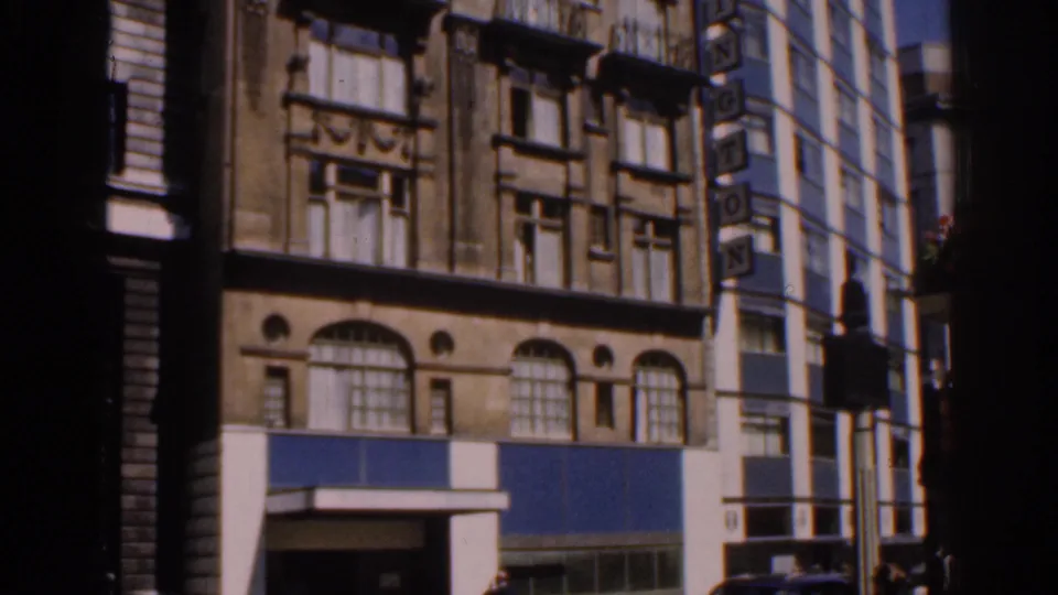 1960s London street view showing a blue-fronted building with arched upper windows, partly blocked by dark frame edges.
