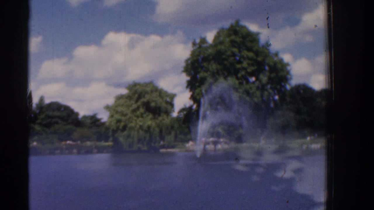 Fountain and trees across a pond, with rippled water filling the lower frame.