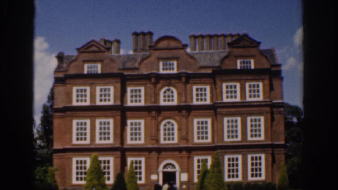 Similar view of the mansion facade with entrance and garden shrubs visible.