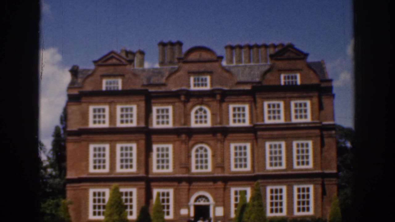 1961 Ireland 8mm frame showing a closer visitor view of the red brick mansion, with rows of white windows and greenery near the entrance.