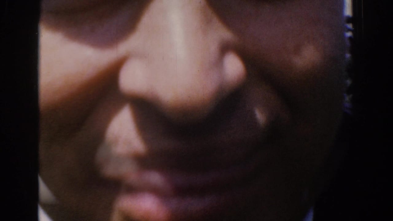 A tightly framed close-up from the 1961 Ireland footage shows the man's face as he moves very near the camera.
