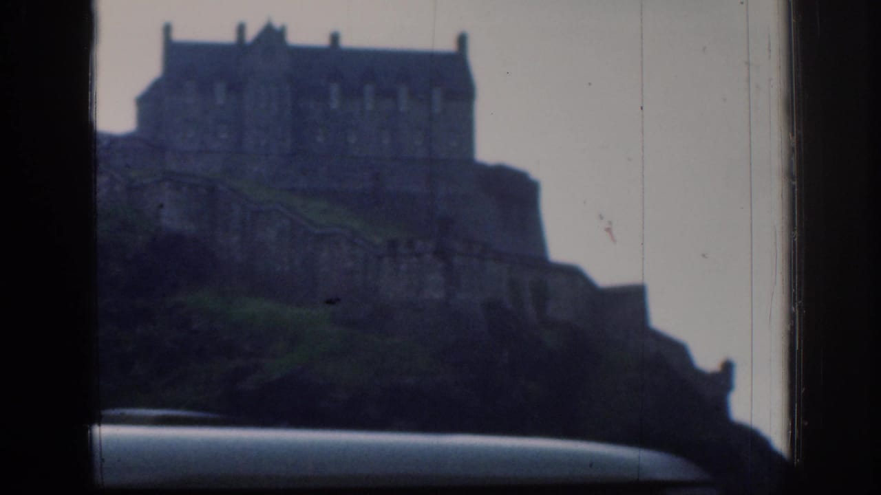 1961 8mm tourist view of the metadata-identified Edinburgh Castle above a car roof, with soft focus and visible scratches.
