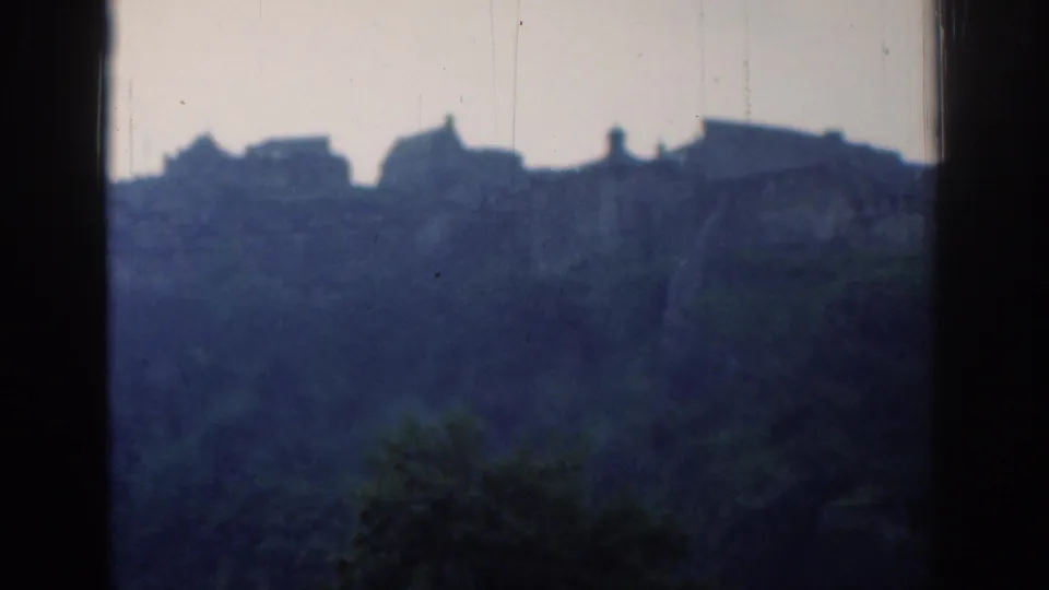 1961 London 8mm frame showing distant hilltop buildings above trees, seen through dark window-like borders.
