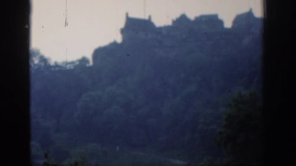 Distant 1961 London hillside view with soft building outlines, trees, dark borders, and visible film wear.