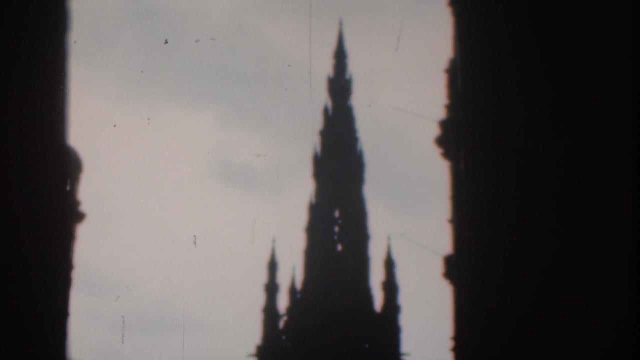 1961 London 8mm frame showing a tall spire in dark silhouette against a pale sky, viewed through a shadowed opening.