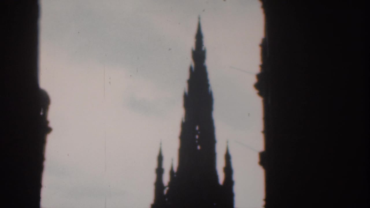 1961 London 8mm frame of a silhouetted church or civic spire against a pale sky, bordered by dark foreground architecture.