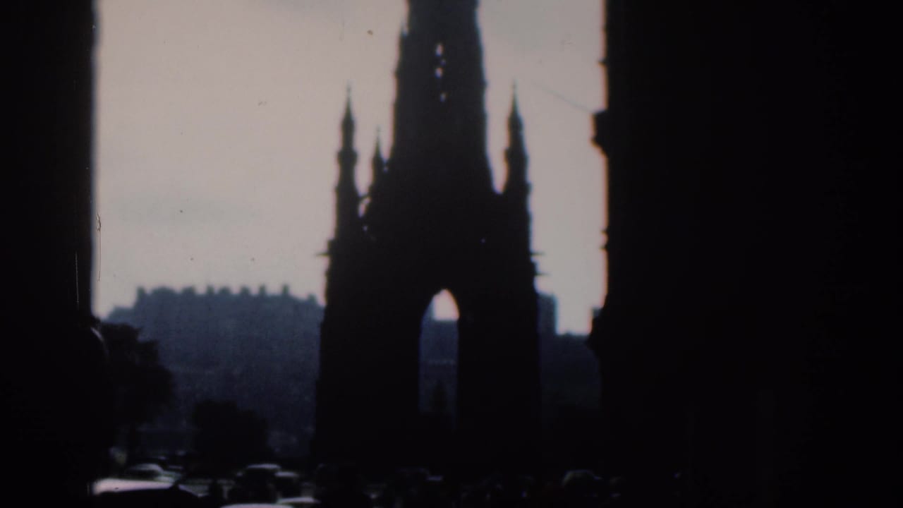 A Gothic arch tower appears beyond dark street edges and distant buildings.