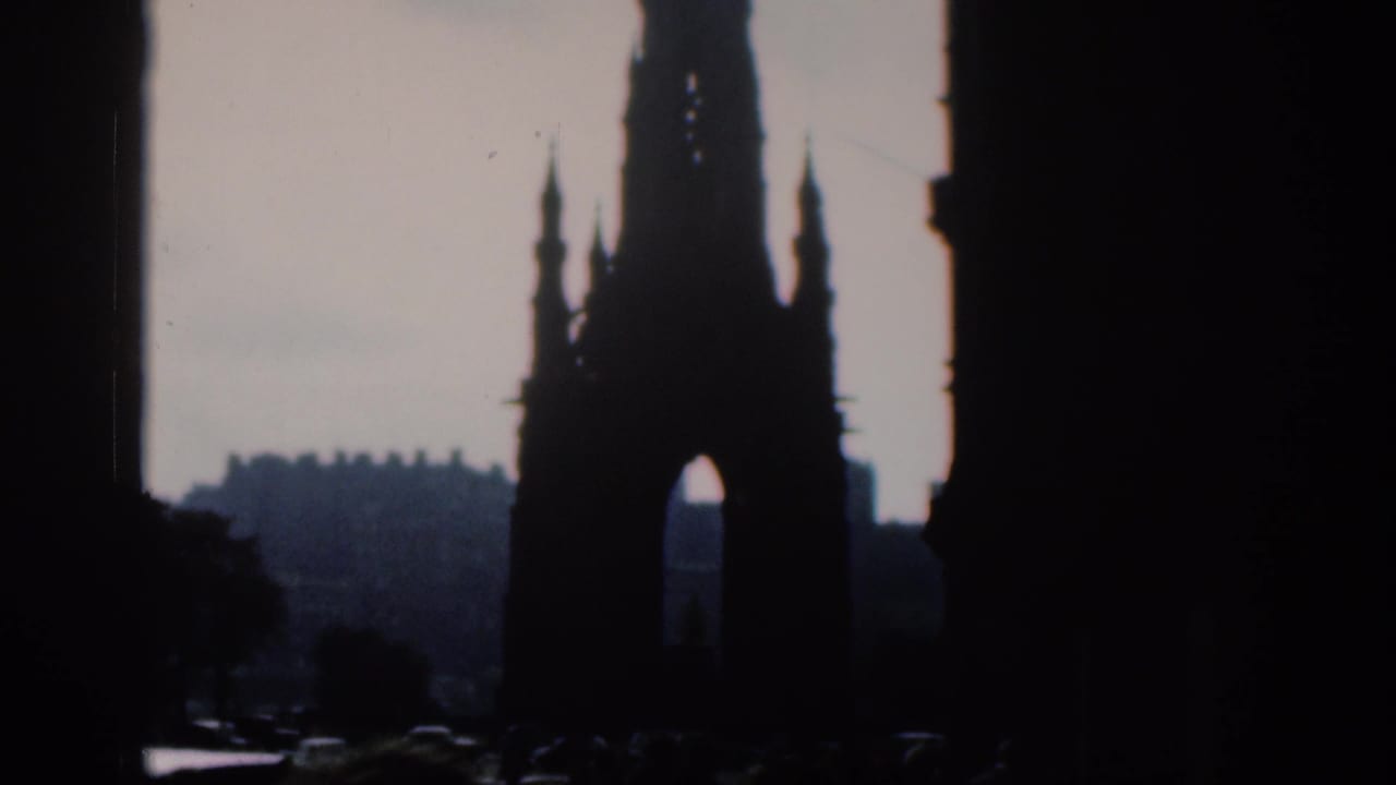 The frame shows a tall Gothic monument in silhouette with faint cars and pedestrians below, consistent with cataloged 1961 city footage.