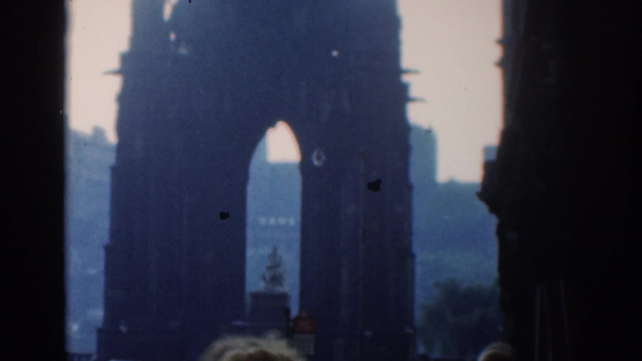 1961 London 8mm frame showing a large dark arch silhouetted against pale sky and distant urban forms.