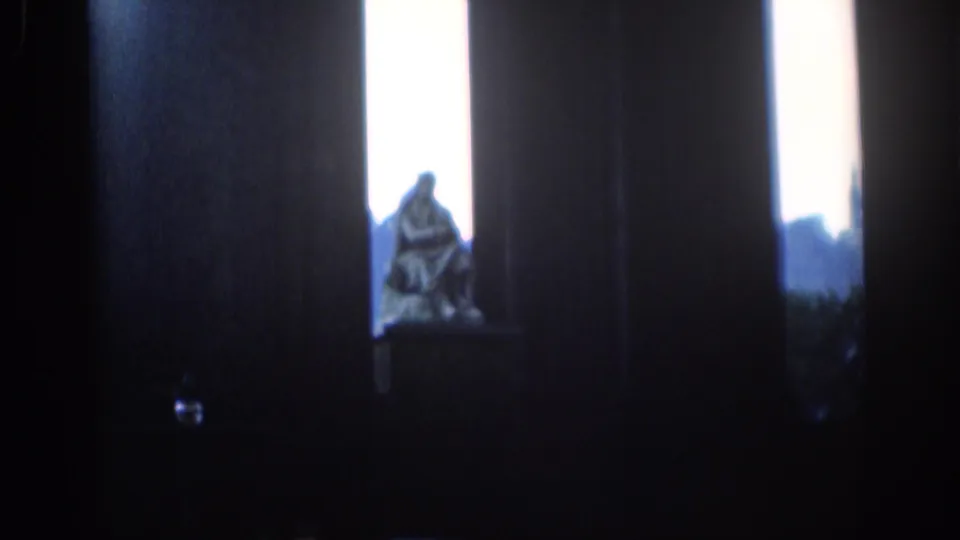 1961 London frame showing a seated statue against bright haze, framed by dark architectural supports.