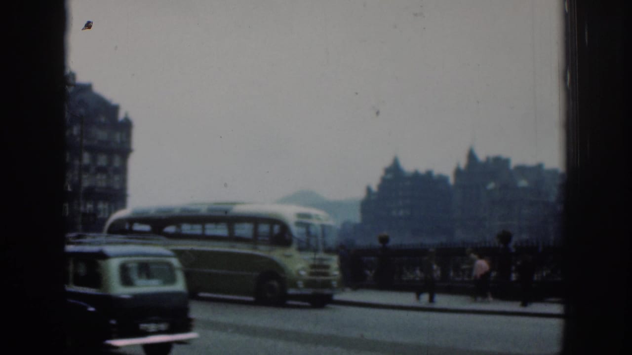 Green-and-cream bus and a small car pass pedestrians near bridge railings.