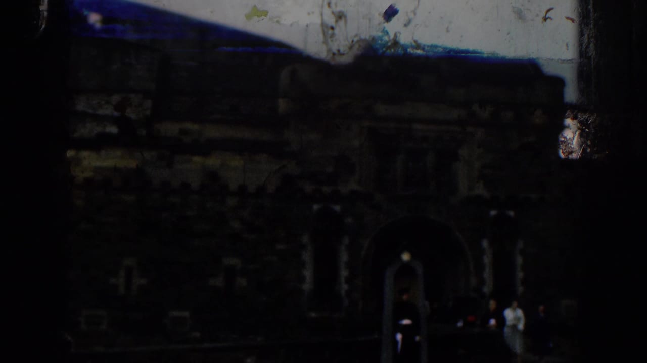 Dark stone castle entrance with a guard and small groups of visitors nearby.