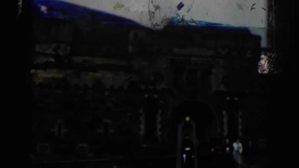 1961 London 8mm frame showing a dark stone arched entrance, a sentry post, and tourists near the gate.