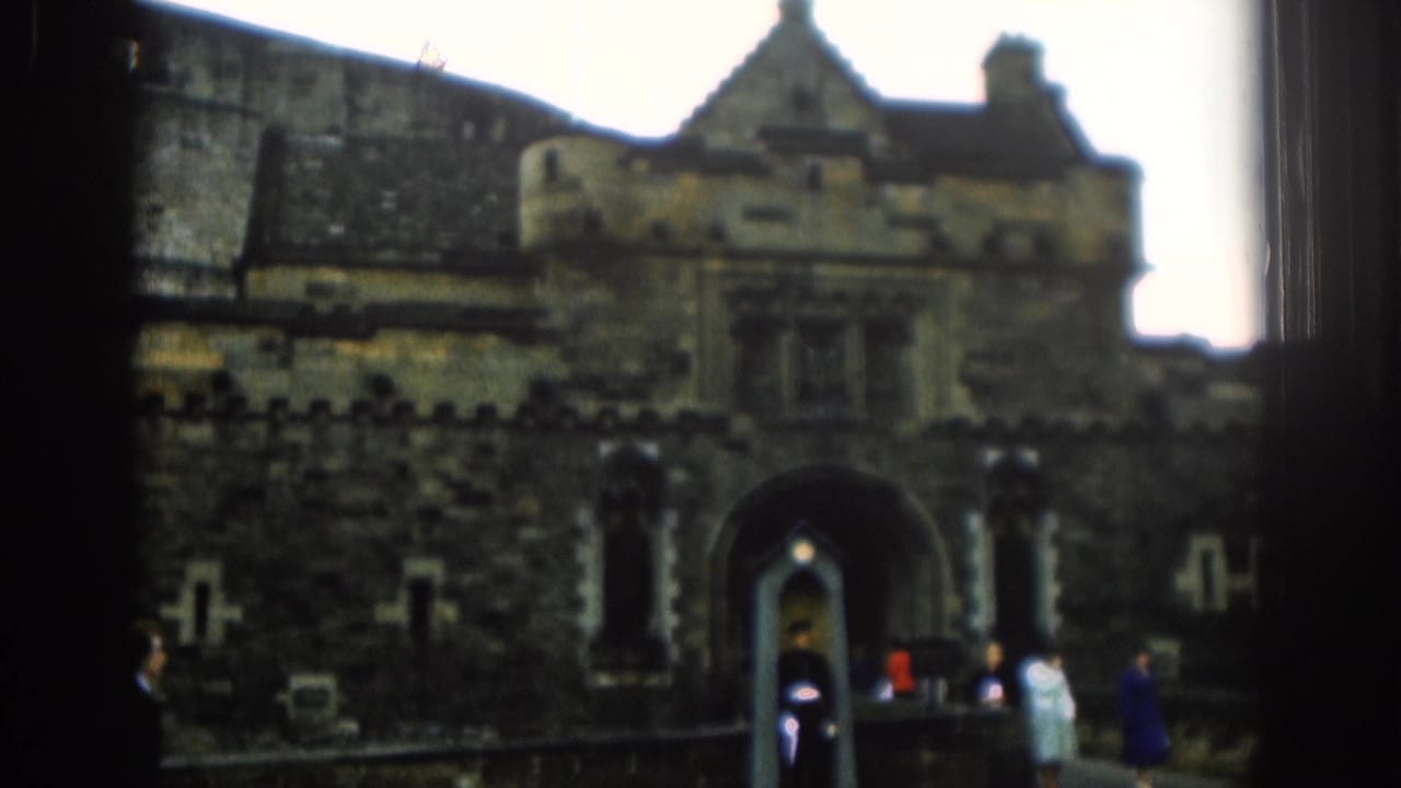 1961 London visitor footage frames a castle-like stone entrance with a guard standing post as tourists pass nearby.