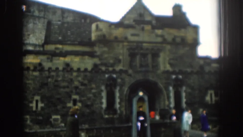 1961 London 8mm frame shows tourists near a guarded arched entrance, with the sentry box centered below the stone facade.
