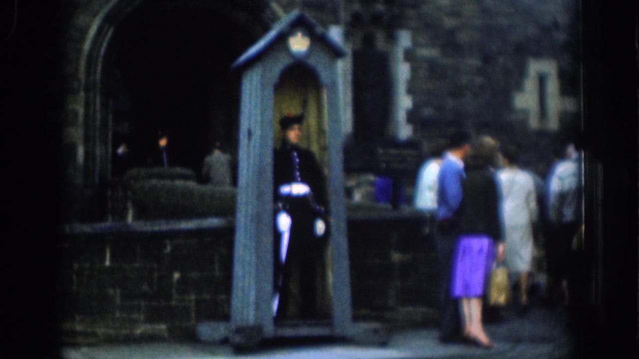 1961 London 8mm frame focuses on a uniformed guard in a sentry box while tourists stand nearby at the stone entrance.