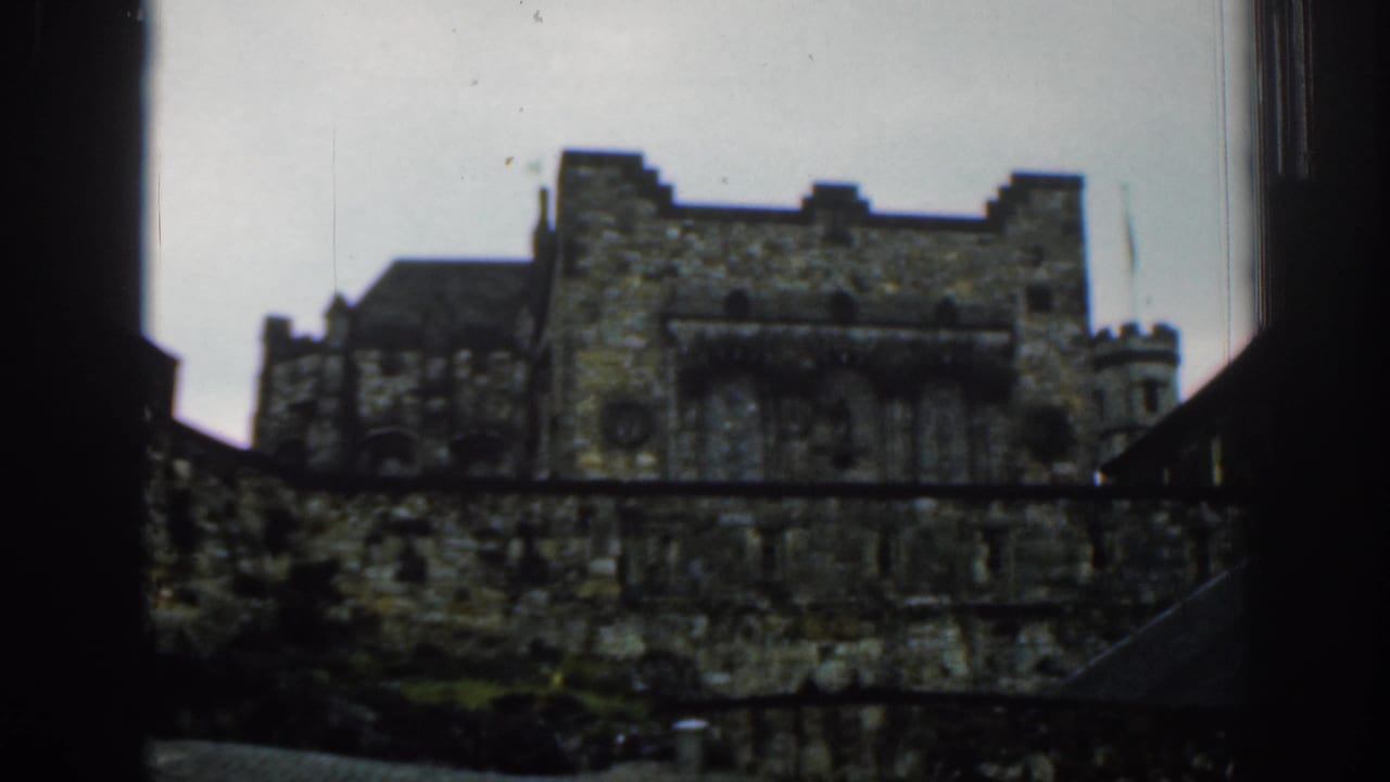 1961 London 8mm frame showing a historic stone building with crenellations and tower forms, seen through dark side framing.