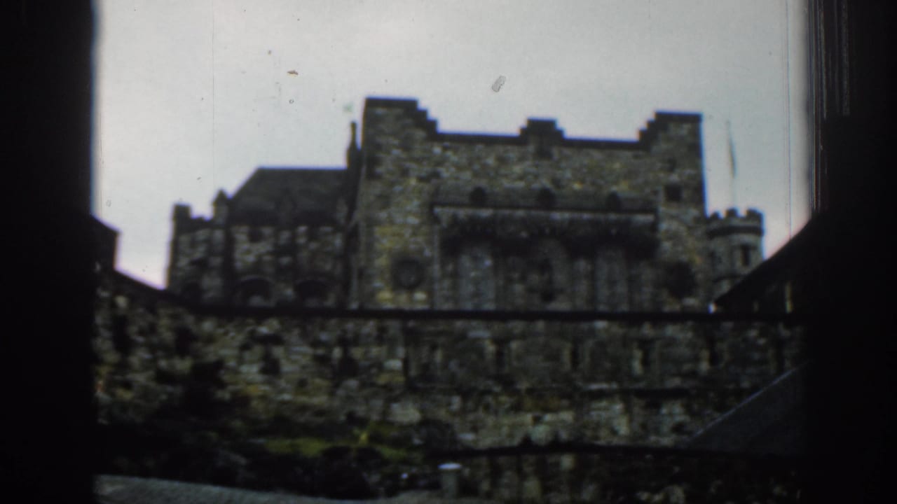 Dark-framed view of an old grey stone building under an overcast sky.