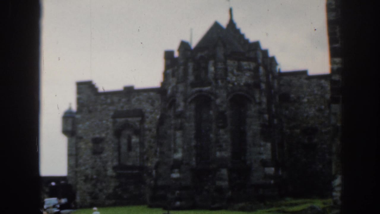 Wider 1961 London home-movie view of the church exterior, showing a stone facade, dark arched entrance, and grass foreground.