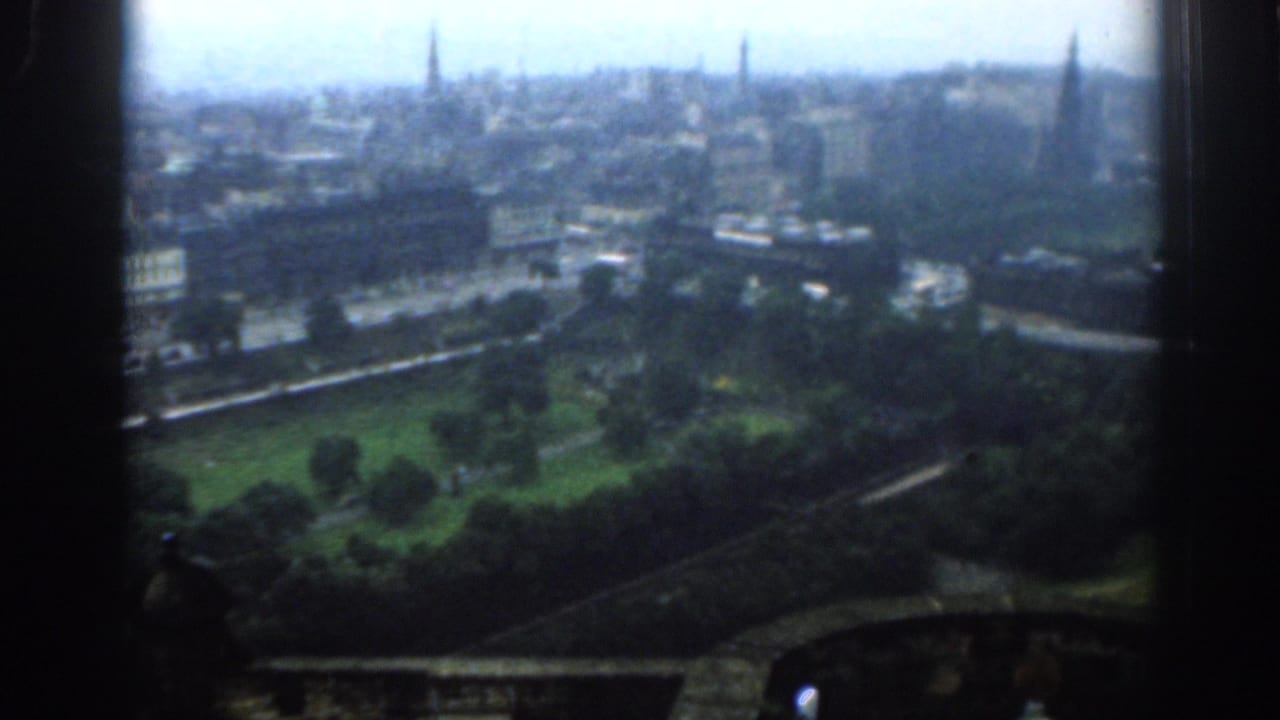 1961 London skyline from a high vantage, with green parkland below, streets and buildings mid-frame, and distant church spires.