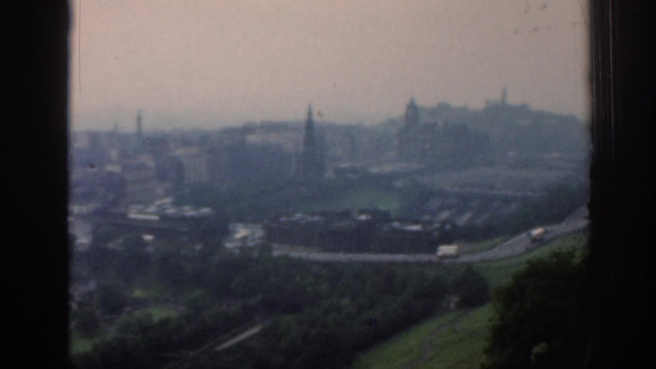 1961 London panorama with green park slopes in the foreground, roads and rooftops below, and a hazy skyline with spires in the distance.