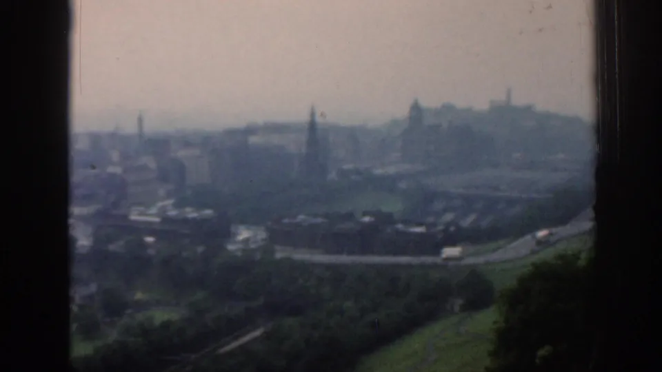 1961 London panorama with green park slopes in the foreground, roads and rooftops below, and a hazy skyline with spires in the distance.