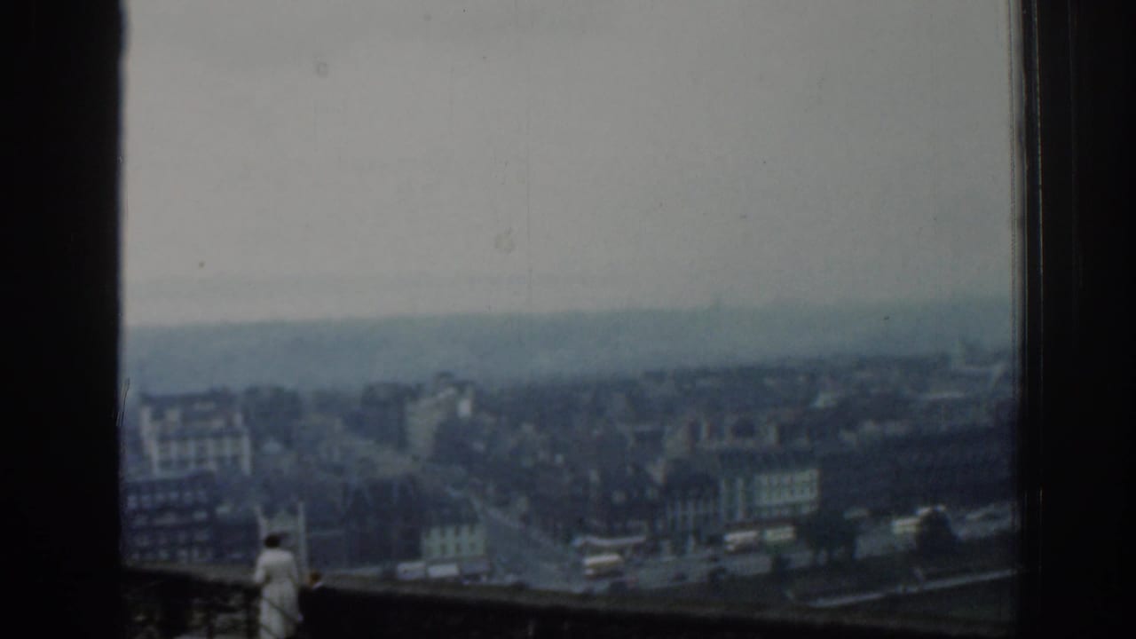 A soft 8mm view over London streets and buildings, with a small visitor figure at the bottom of the frame.