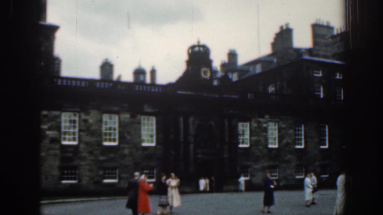 1961 London visitor footage with people spaced across a courtyard before a historic stone building and central clock feature.