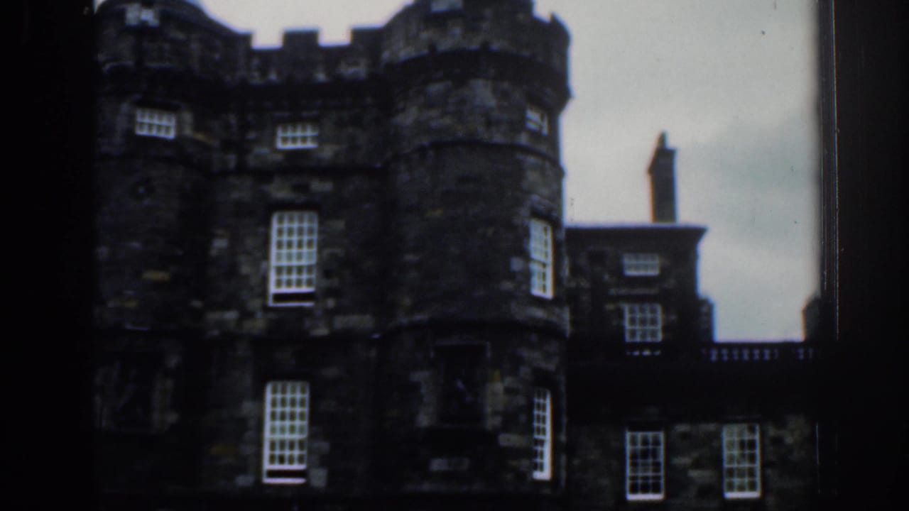 1961 London frame showing dark stone castle-like architecture, including a round turret, windows, and connecting facade.