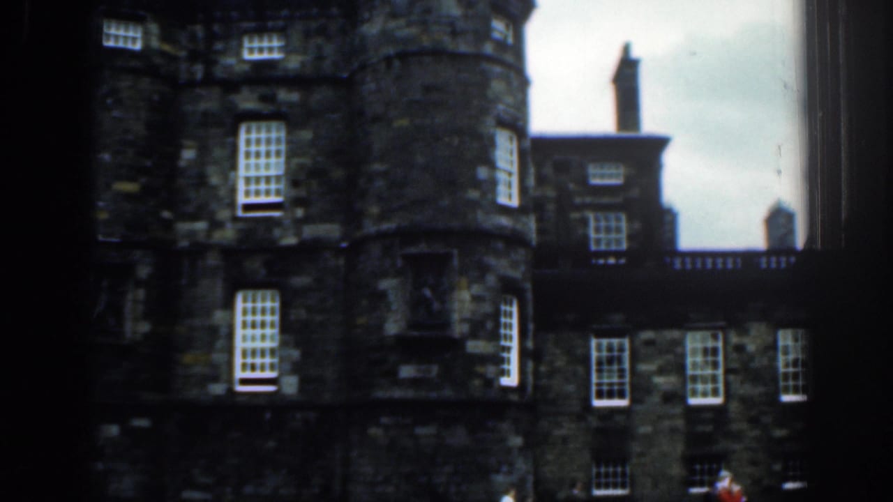 Historic stone building listed as London, with rounded tower sections, white-paned windows, chimneys, and a dark vertical frame edge.