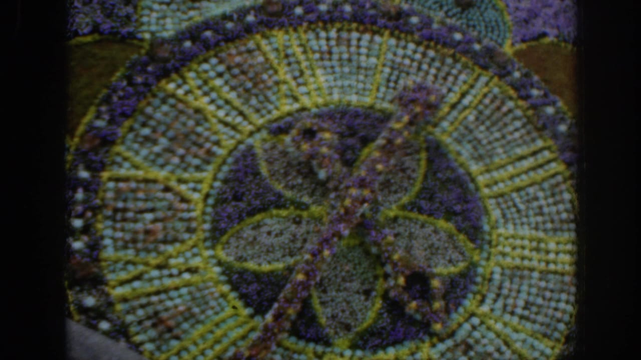 Close view of a circular floral mosaic with purple, green, and yellow planting.