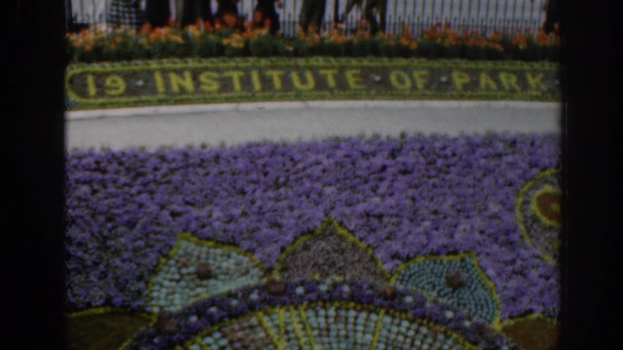 Formal flower bed with planted lettering, railings, and visitors behind the display.