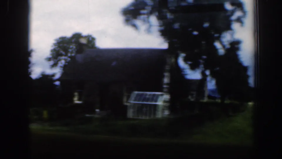 Rural Scottish building scene with trees, a small glasshouse-like structure, and dark 8mm exposure from the moving viewpoint.