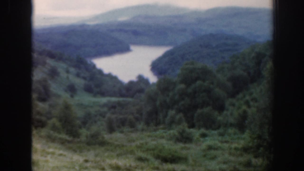 Loch winding between green hills, seen through dark window framing.