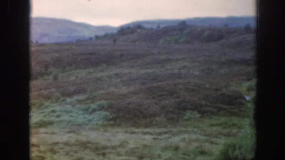 1961 Scotland 8mm frame showing a quiet rural pasture and distant hillside through soft focus and faded color.