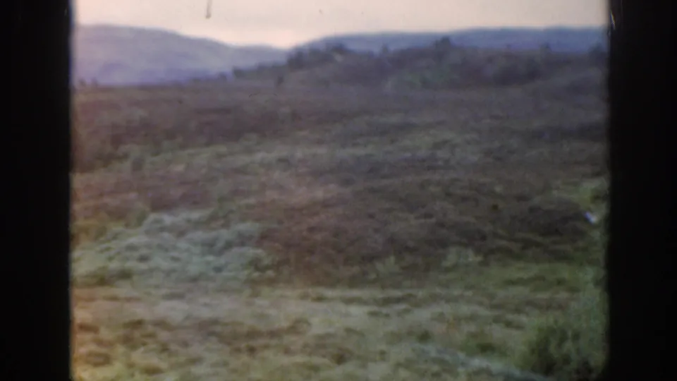 1961 Scotland 8mm frame with color-faded moorland pasture, distant low hills, and no visible people or buildings.