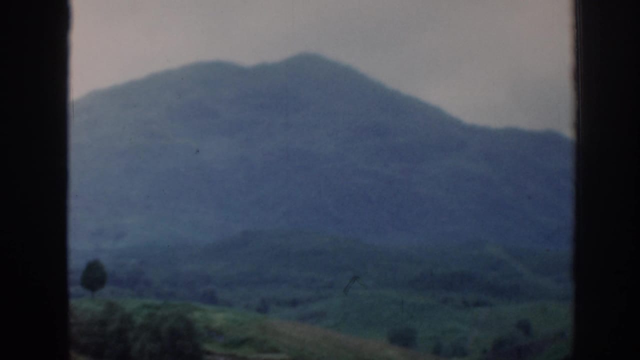 Distant mountain ridge and green valley framed by a car window.