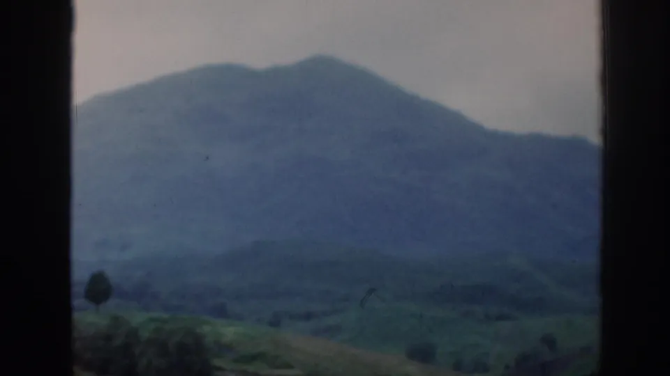 1961 Scotland 8mm frame showing a distant mountain ridge and green valley through a car window.