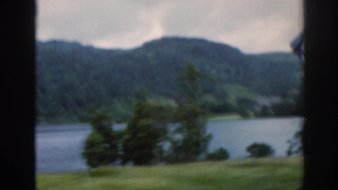 Soft view of loch water and wooded hills seen through a dark window-like frame.