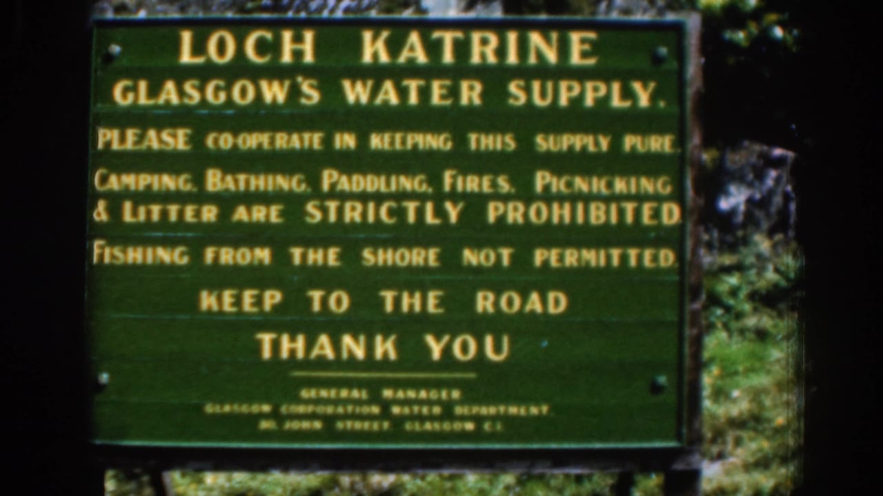 Green Loch Katrine water-supply notice with yellow lettering beside trees.