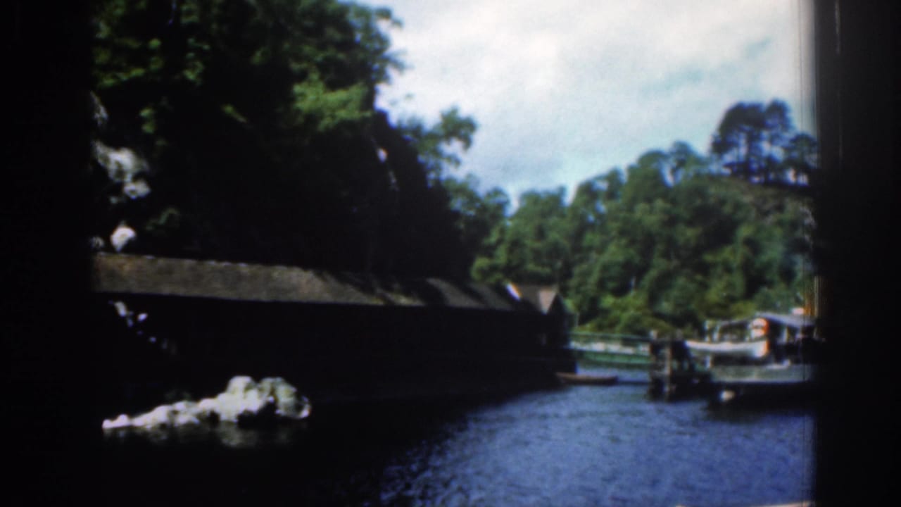 Covered wooden bridge beside water with boats near the shoreline.