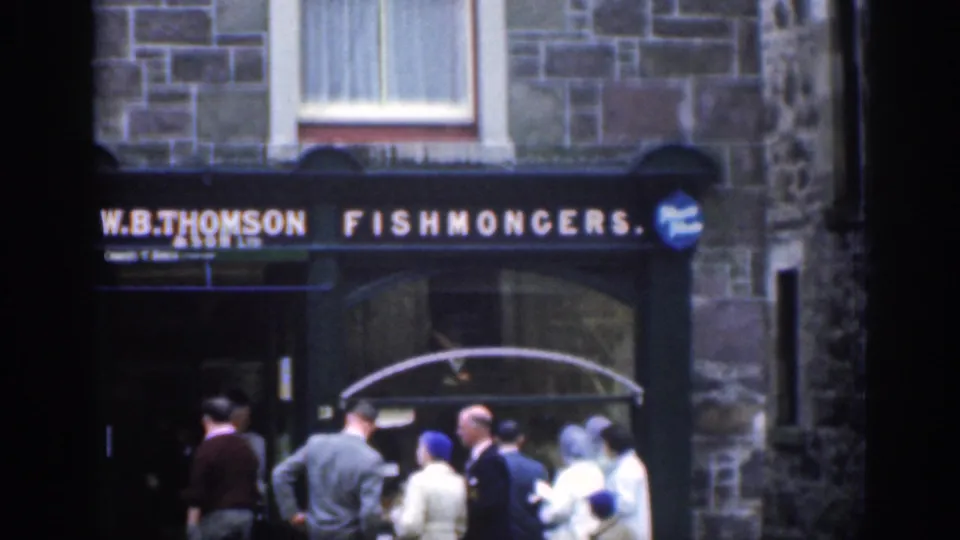 1961 Scotland street view with people in period dress gathered by the W.B. Thomson Fishmongers sign.