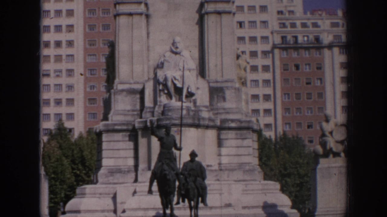 1966 Spain 8mm frame showing a grand stone monument with seated and equestrian statues backed by apartment blocks.