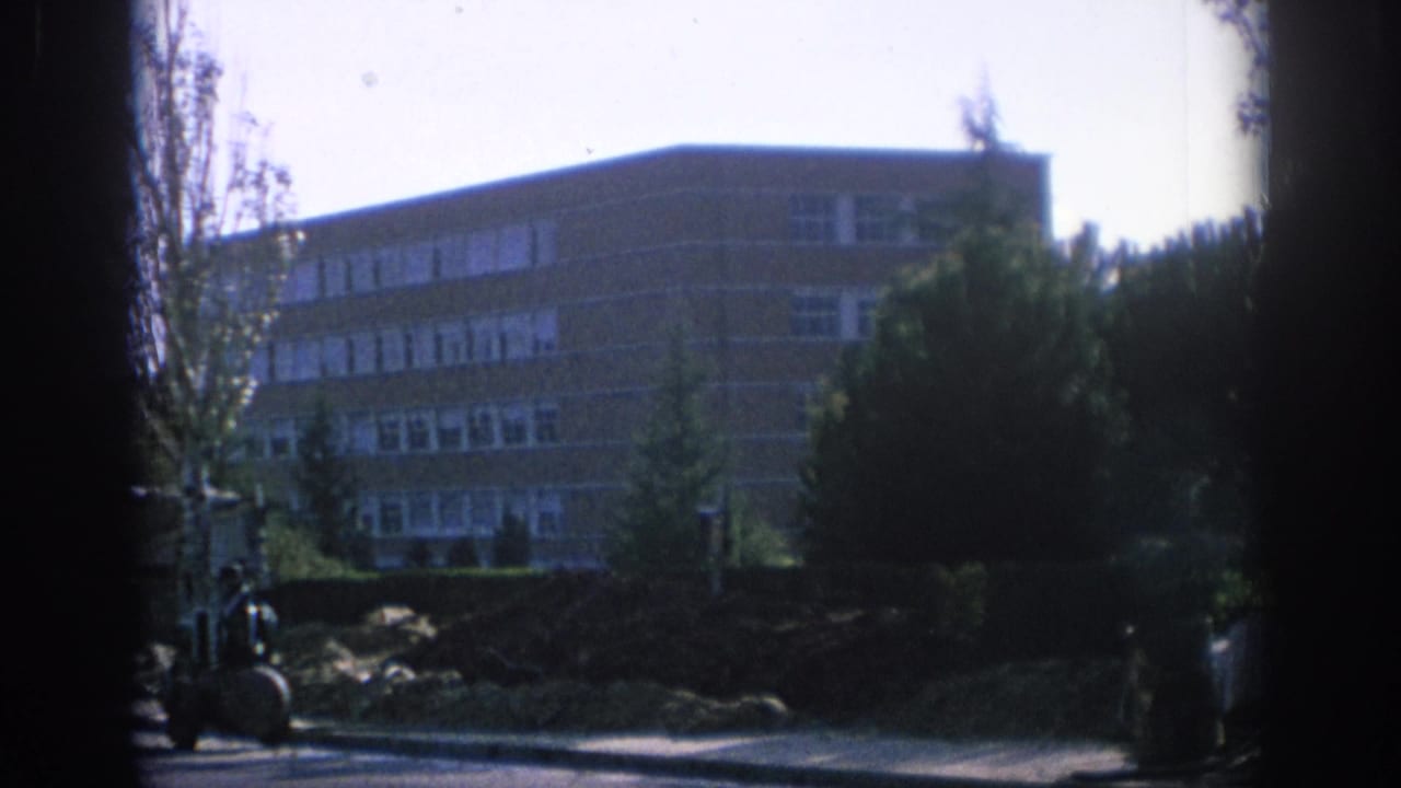 1966 Spain frame with a brick residential block, trees, and heavy dark framing across the center of the view.