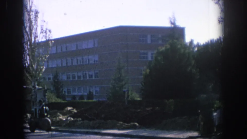 1966 Spain frame with a brick residential block, trees, and heavy dark framing across the center of the view.