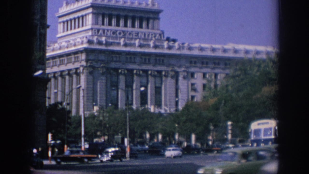 Banco Central building behind moving city traffic and trees.